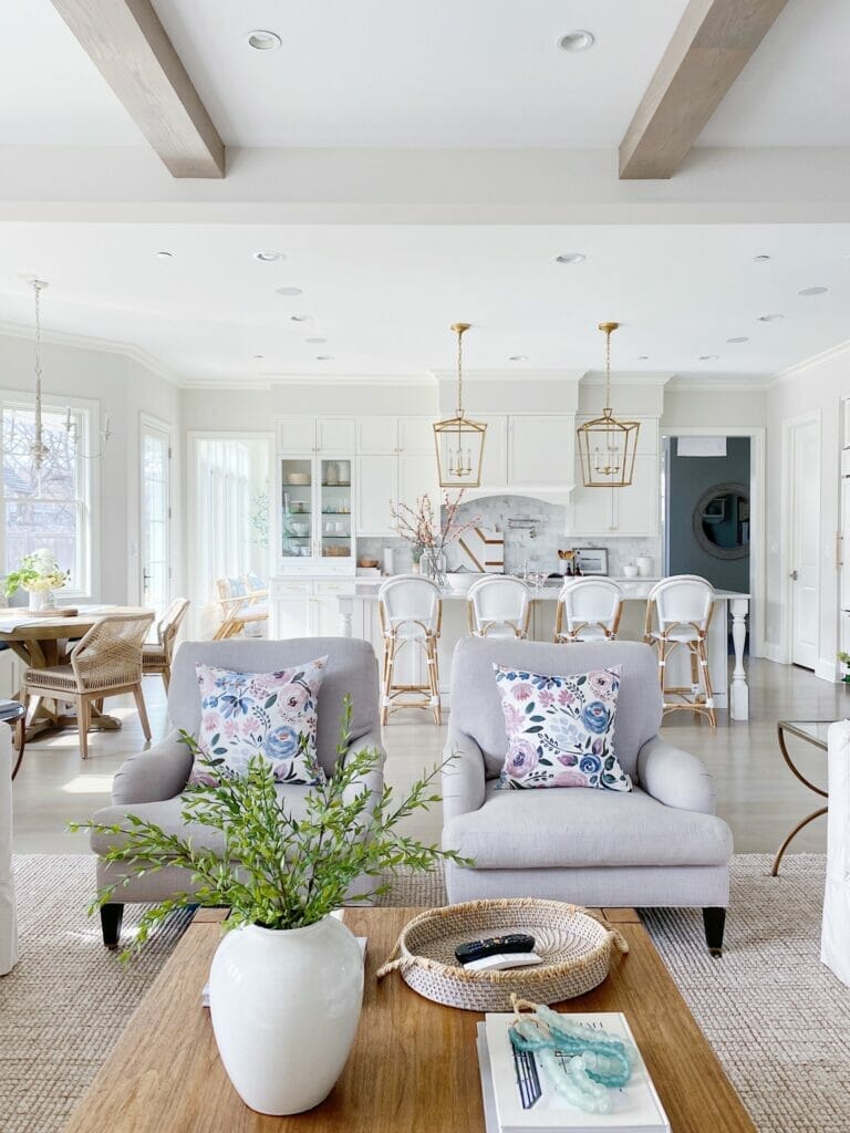 Open kitchen and living room design, Serena and Lily riviera stools and Darlana brass lanterns. White kitchen cabinets and benjamin moore classic gray walls.