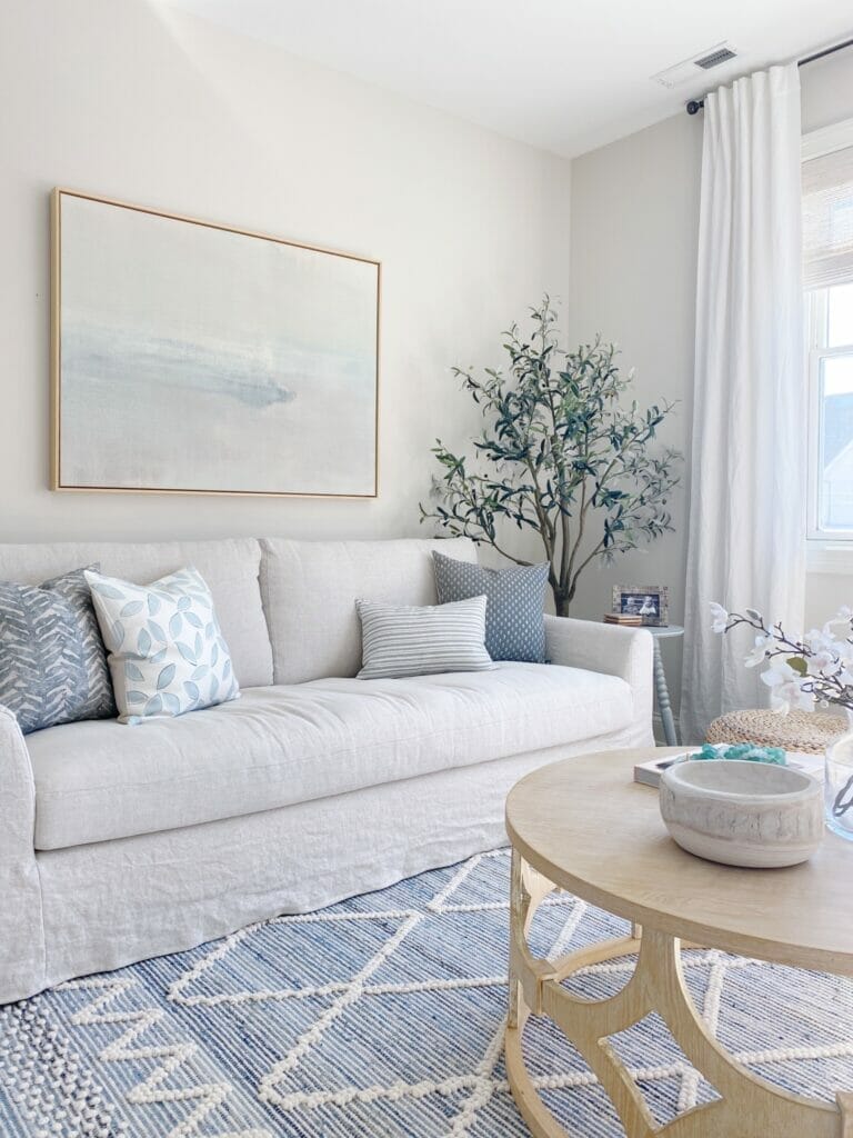 Living room features Serena & Lily Ryder denim rug, Benjamin Moore classic gray walls, pretty abstract art and Ikea farlov sofa, swivel chairs and simple coffee table styling.