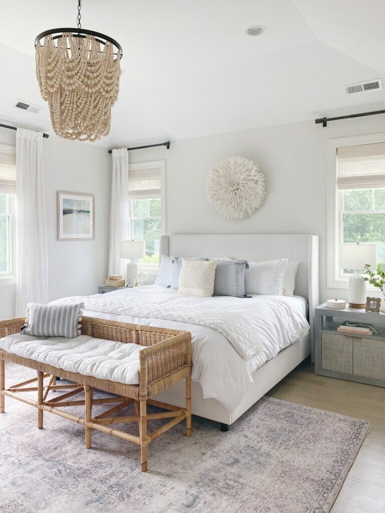 Bedroom featuring Gap Home pillows and frayed edge quilt, Benjamin Moore classic gray walls, upholstered bed and rattan bench