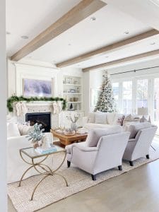 Neutral living room with faux christmas tree, pretty holiday mantle decor and festive coffee table styling