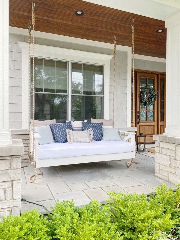 outdoor hanging daybed layered with pillows on a porch | How to Mix and Match Throw Pillows