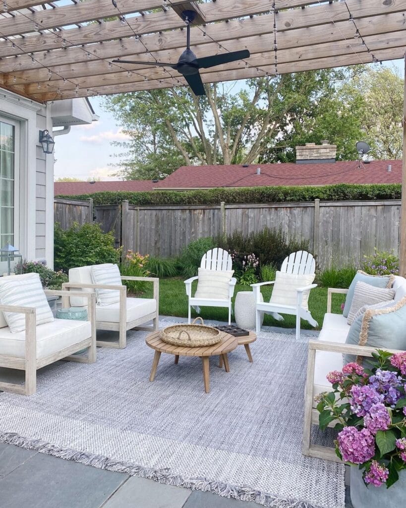outdoor seating area with chairs, and couch with neutral color cushions and pillows with a blue and white printed outdoor rug